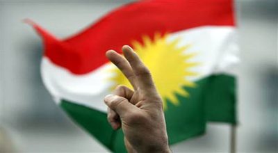 A protester make a victory sign with his hand in front of a Kurdish flag during a demonstration in Berlin